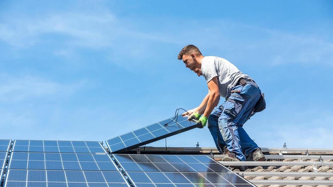Twee installateurs leggen zonnepaneel op dak